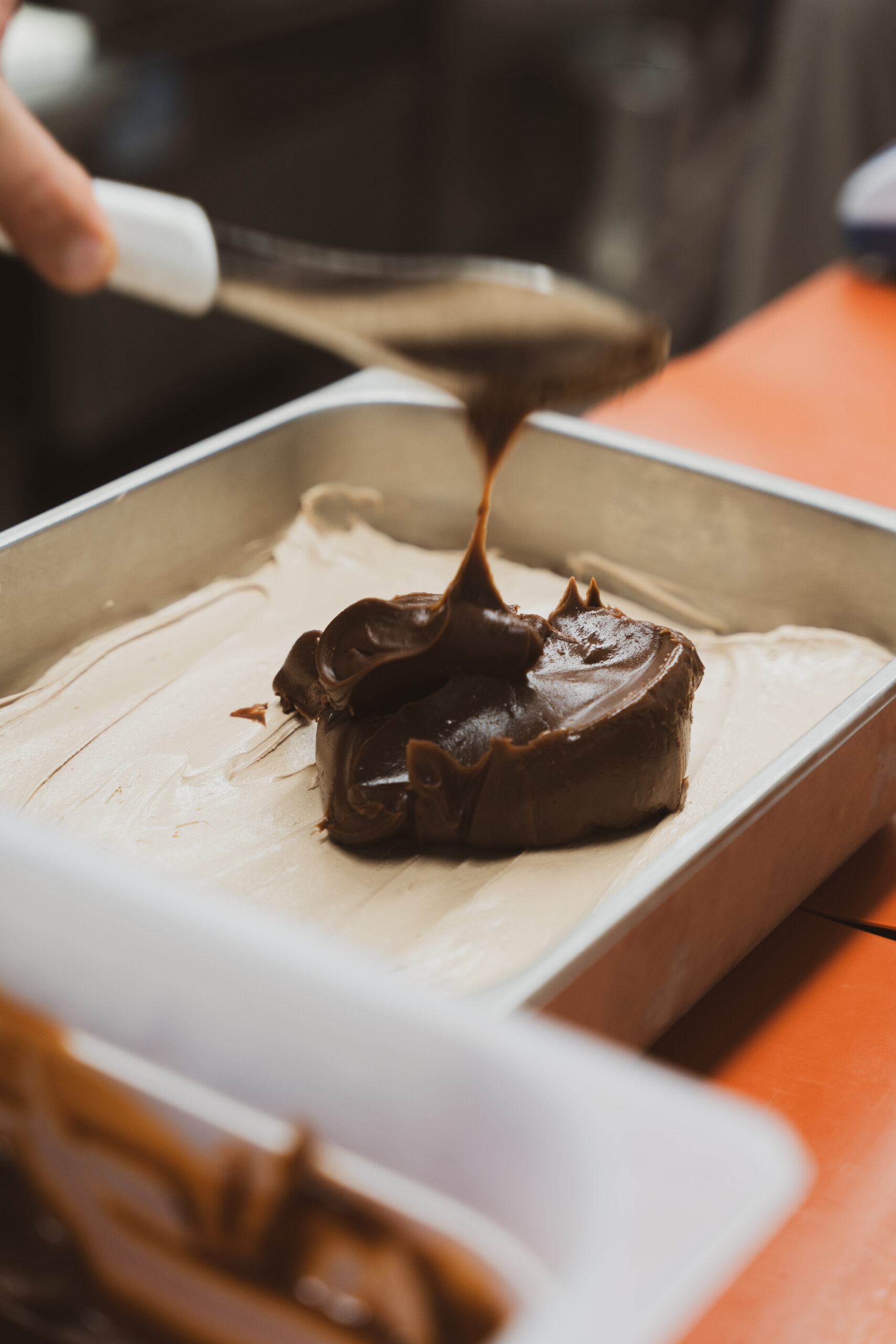 Una salsa scura viene versata a strati sul gelato in vaschetta