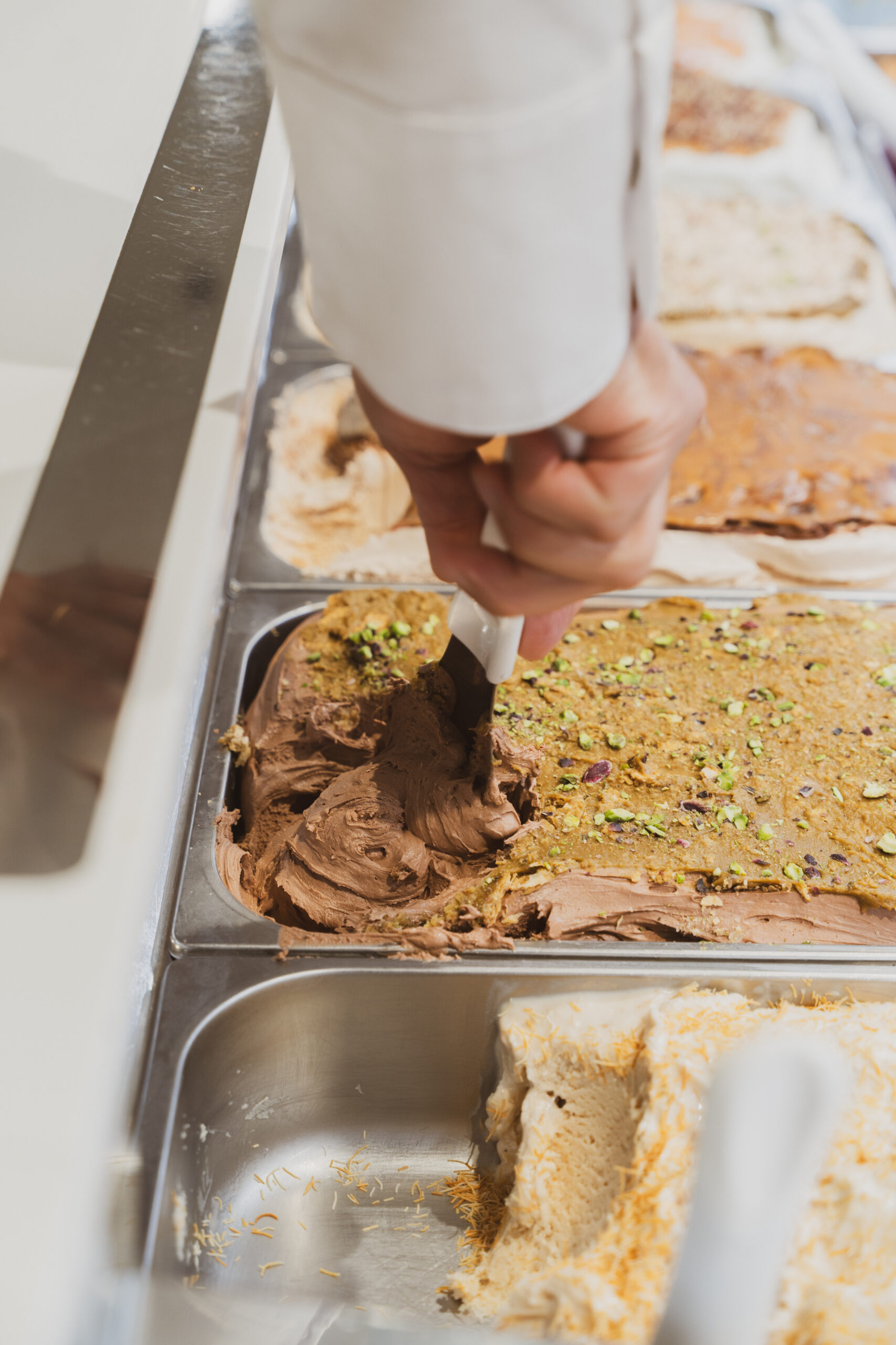 Un gelatiere serve il gelato dalla vetrina con la spatola